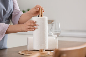 Housewife with paper towels and glass on table in kitchen, closeup