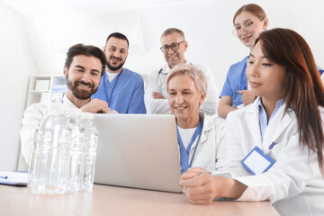 Team of doctors working with laptop at table in clinic