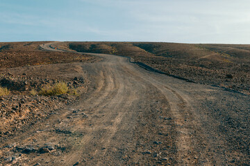 Rocky off-road dirt road crossing a barren volcanic landscape on Fuerteventura island, remote travel route, arid terrain and rugged scenery in the Canary Islands © Katarzyna Ledwoń