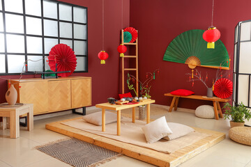 Interior of traditional Chinese room with tea set on table, bench and fans