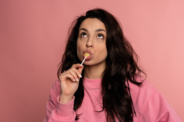 Cute lady licking a yellow lollipop on the plastic stick in front of the camera. Love of sweet food...