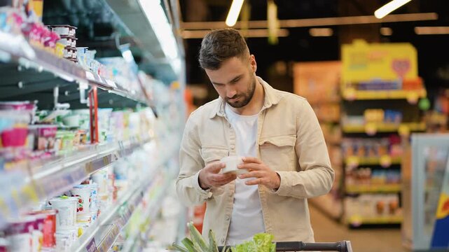 Handsome man choosing dairy products in supermarket grocery store