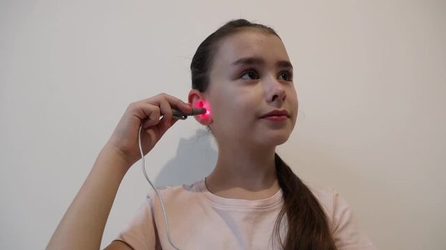 Little girl treating ear with infrared light.