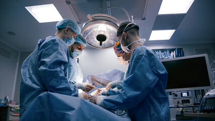 Group of medical professionals in surgical attire performing an operation under bright lights in a sterile environment, showcasing teamwork and precision in healthcare