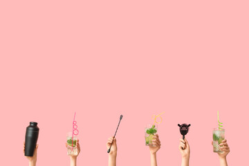 Fototapeta premium Female hands with glasses of tasty mojito, shaker, cocktail strainer and stick on pink background