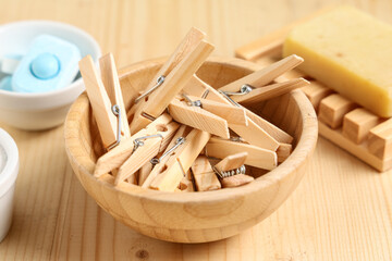 Bowls of wooden clothespins with laundry tablets and soap on brown wooden background