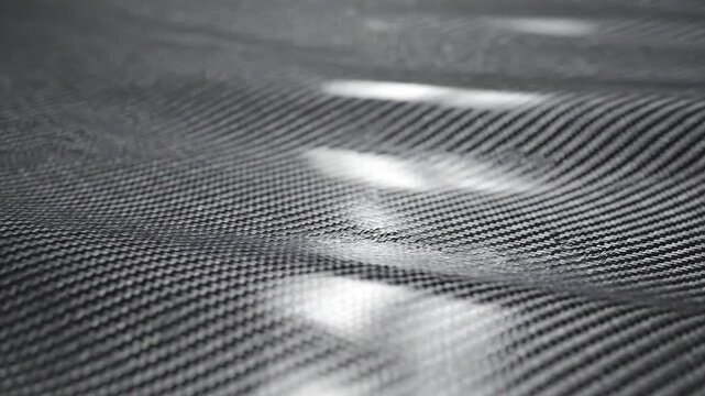Woven Carbon Fiber: Captivating abstract of a tightly woven carbon fiber composite, showcasing intricate texture and patterns under soft lighting.