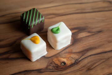An elegant arrangement of artisan white chocolate squares, beautifully decorated and presented on a rustic wooden board. Perfect for gifts and celebrations.