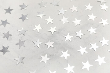 Many silver stars as confetti on grey background