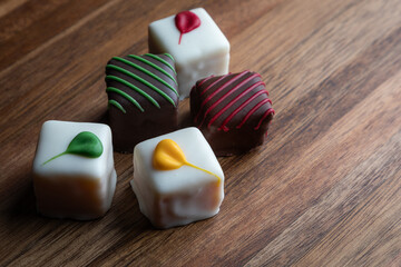 An elegant arrangement of artisan white chocolate squares, beautifully decorated and presented on a rustic wooden board. Perfect for gifts and celebrations.