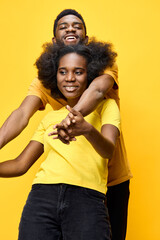 Obraz premium Happy multicultural couple in bright yellow t shirts laughing together against a vibrant yellow background, expressing joy and love