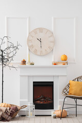 Obraz premium Interior of light living room with white fireplace, cozy armchair, modern lamp and clock