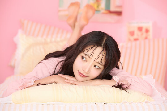 カラフルなベッドレームでリラックスする若い女性のかわいいポートレート