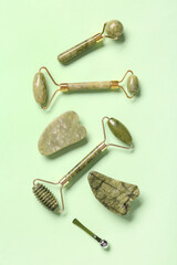 Different facial massage tools on green background