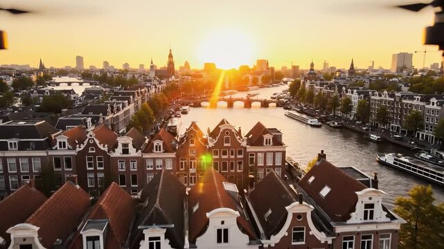 Golden sunlight glows over Amsterdam's charming canals as quaint houses line the waterfront. The picturesque scene captures the beauty of the skyline and serene water reflecting th