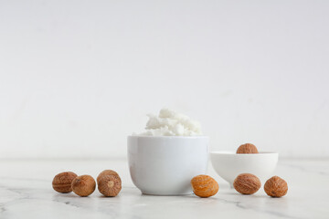 Bowls with shea butter and nuts on light table