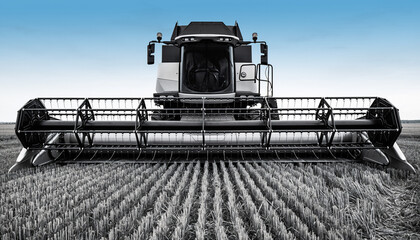 Fototapeta premium Modern Combine Harvester Working in a Golden Wheat Field Under a Clear Blue Sky.