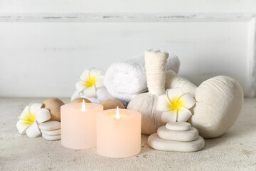 Glowing aroma candles with spa supplies on light background