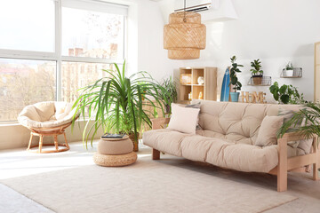 Interior of light living room with sofa and tropical plants