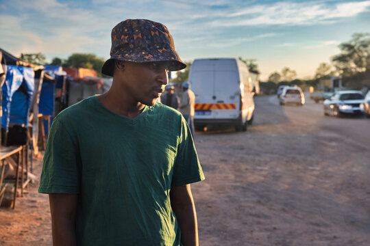 single young african men in old town at station trading area at sunrise, Johannesburg city, South Africa, casual clothing, road with cars