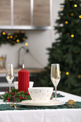 Table setting with Christmas wreath and burning candle in kitchen, closeup