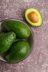 Bowl with fresh ripe avocados on dark background