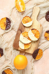 Wooden board with chocolate dipped dried orange slices on beige background