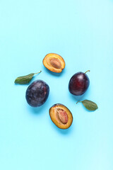 Fresh ripe plums and leaves on blue background