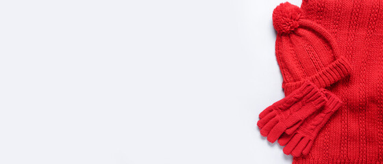 Red knitted gloves with warm scarf and hat on white background