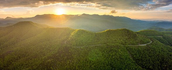 Winding parkway road near Mount Mitchell in mountain forest with green canopies in summertime evening. Driving in North Carolina wild woods nature in summer