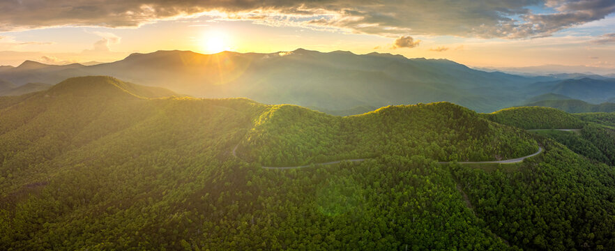 Winding parkway road near Mount Mitchell in mountain forest with green canopies in summertime evening. Driving in North Carolina wild woods nature in summer