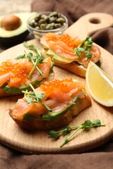 Delicious bruschettas with caviar, salmon, avocado and microgreens served on table, closeup