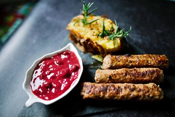 Cooked sausages served with baked potato and sauce