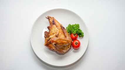Top view of roasted chicken served on white plate with tomato and parsley garnish. Minimal food photography with copy space, ideal for menu design, food advertising, healthy protein concepts.