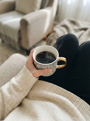 Cozy lifestyle moment of a person holding a cup of hot coffee while relaxing indoors