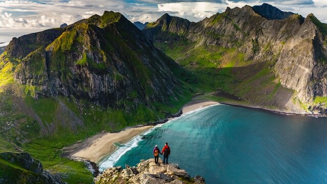 Adventurers enjoy panoramic views over the stunning Ryten Kvalvika Beach Trail in Lofoten, Norway.