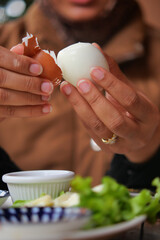 Person peeling a boiled egg at a dining table