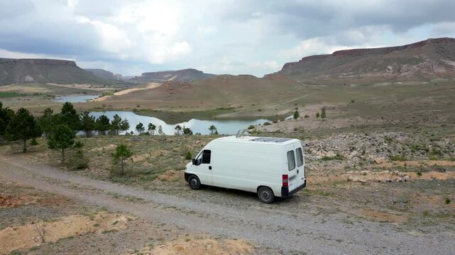 Drone aerial view of camper van off road near Akkoy Dam lake reservoir in Turkey featuring roof mounted solar panels