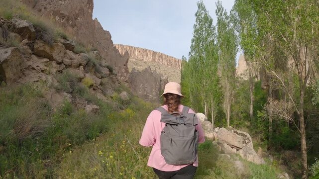 Woman backpacking exploring Soganli Valley with ancient cave houses and green nature in Cappadocia, Turkey
