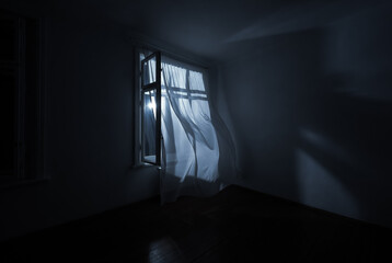 The wind from the window flutters the curtains in the old house in the moonlight.