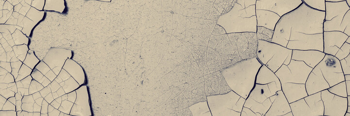 Peeling paint on the wall. Panorama of a concrete wall with old cracked flaking paint. Weathered rough painted surface with patterns of cracks and peeling. Panoramic texture for background and design.