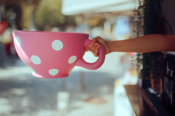 Hand of a Street Vendor Holding a Huge Pink Cup of Coffee. Vendor in a coffee kiosk offering a big sale on warm caffeinated drinks