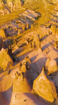 Vertical video. Goreme, Nevsehir, Turkey. Detailed exploration of Devrent Valley revealing intricate erosion details and mineral variations in sunset light.. Aerial View. Rich colors