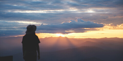 Fototapeta premium Rear view of a woman looking at mountain views with sunset sky