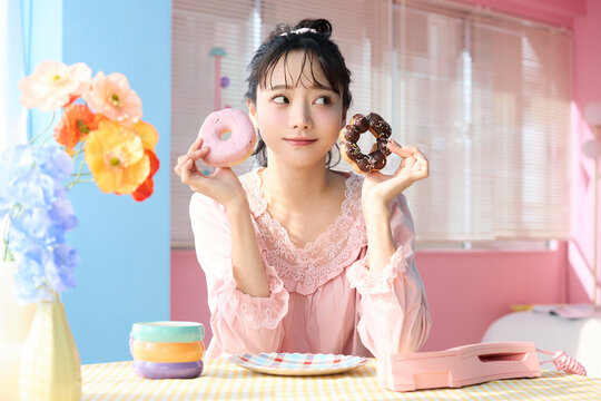 カラフルな部屋でドーナツを食べるかわいい女性のポートレート