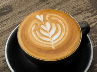 Hot coffee, a hot latte in a mug on a wooden table.