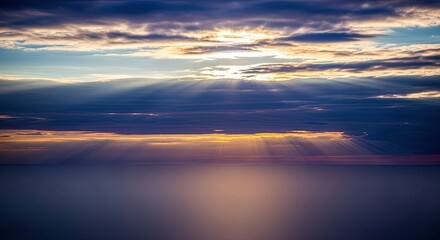 Sunlight filtering through clouds over the ocean at sunset.