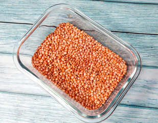Red Lentils (Masoor Dal) in Glass Container on Wooden Background