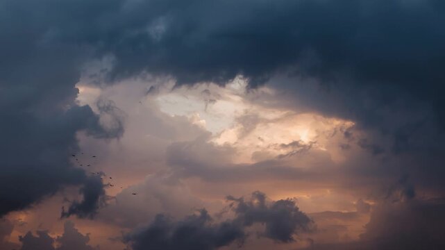 Dramatic dark clouds with a bright opening in the sky and a flock of birds stormy
