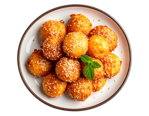 Golden sesame balls piled high on a plate, garnished with fresh mint